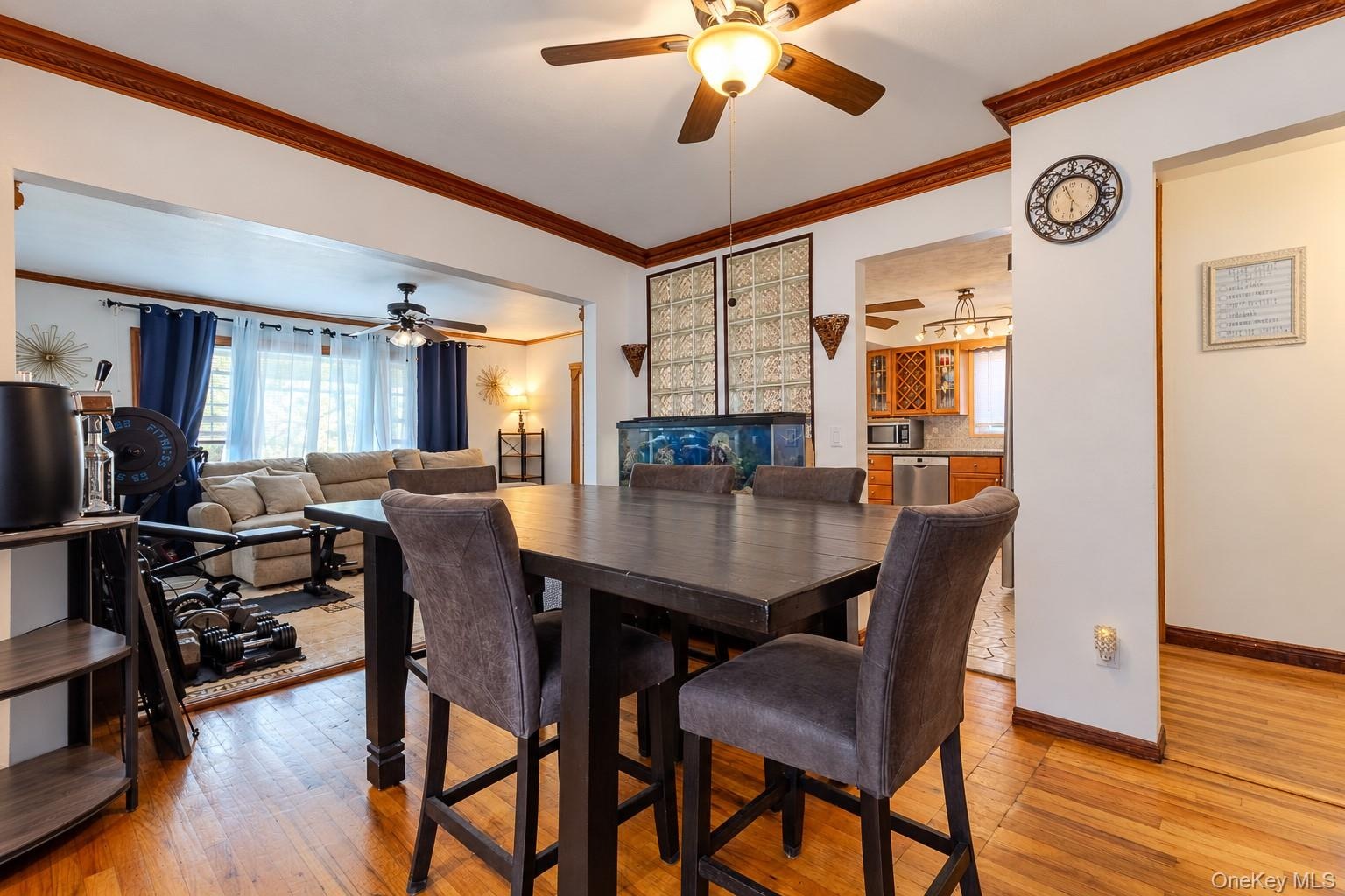 Dining area featuring wood-finish flooring, crown molding, and a central ceiling fan with integrated lighting