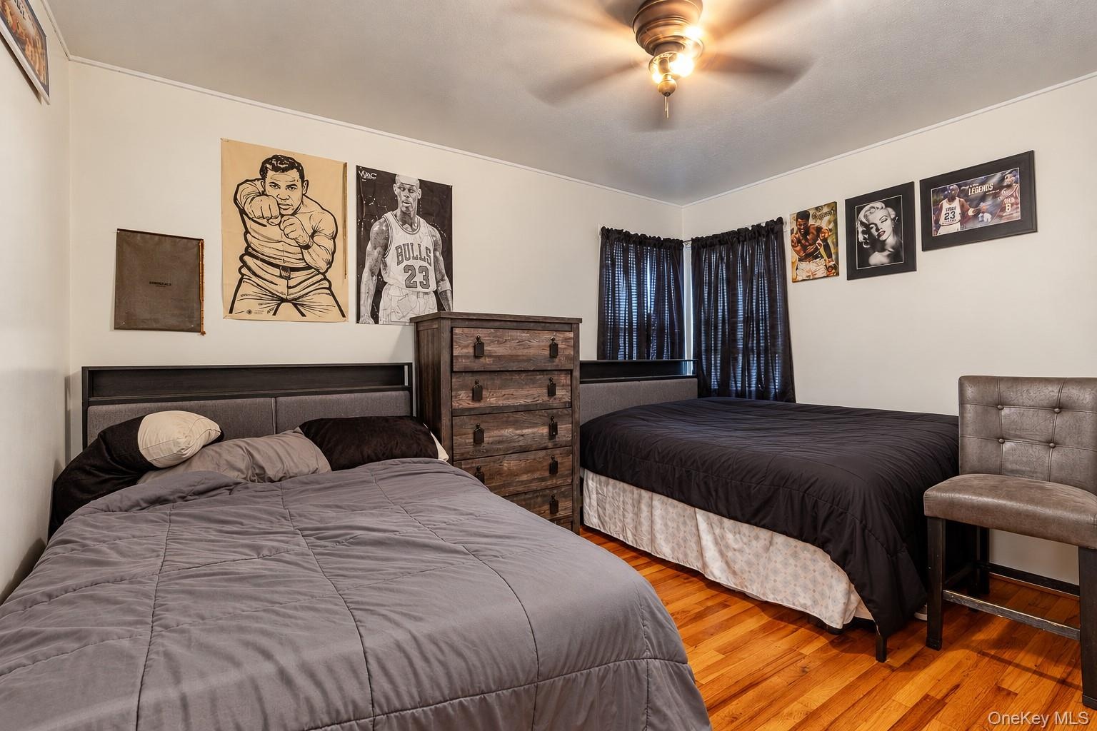 Interior room featuring wood-finish flooring, a ceiling fan with light fixture, and neutral wall coloring