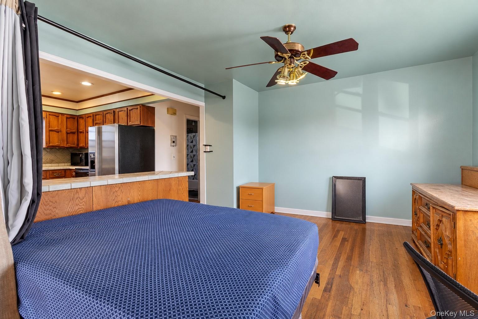 Wood-finish flooring, ceiling fan with integrated lighting, tiled breakfast bar, and kitchen cabinetry