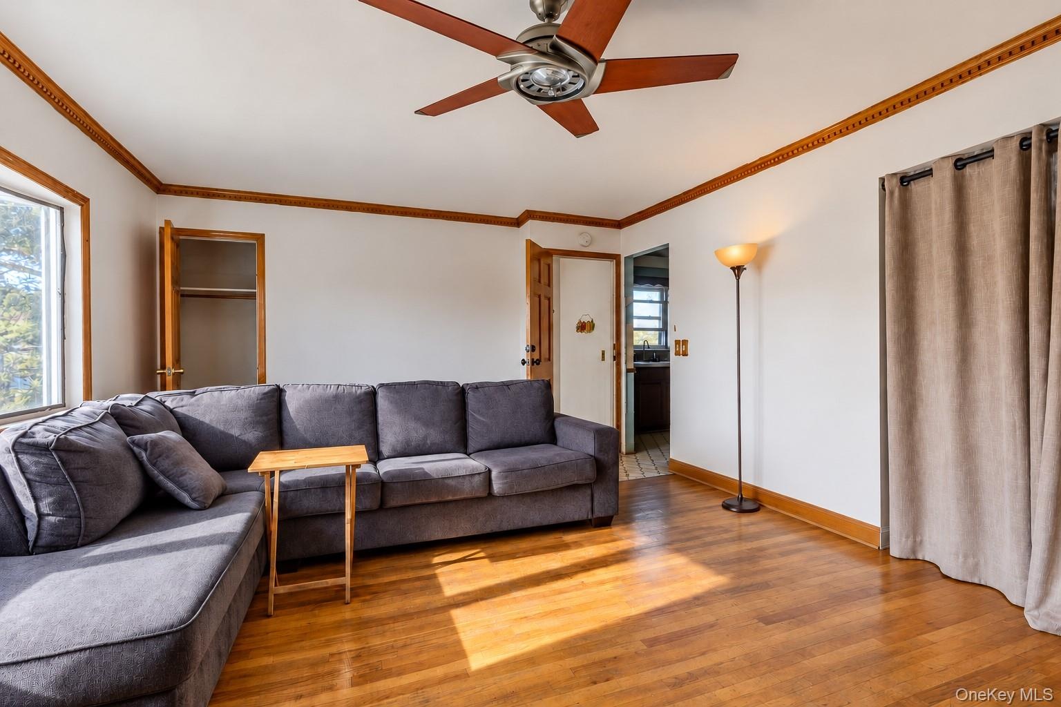 Wood-finish flooring, crown molding, and ceiling fan with integrated light fixture