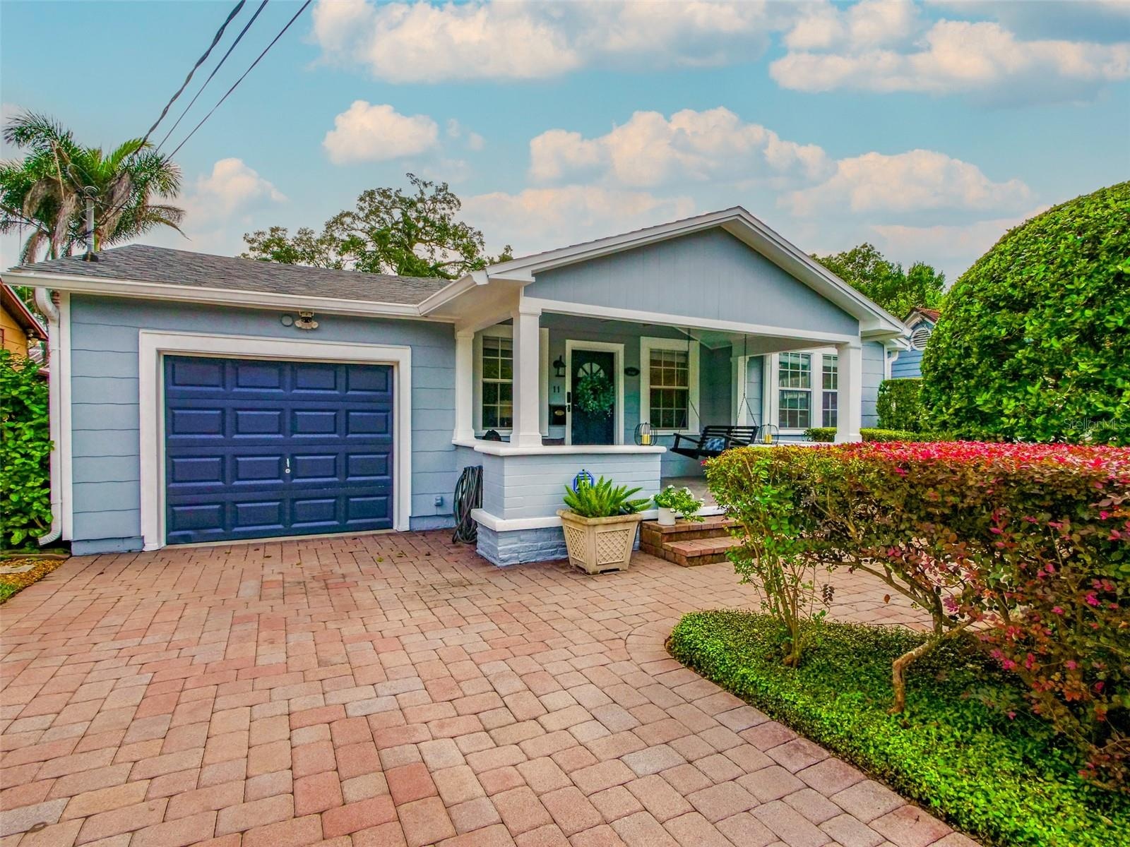 Front exterior with paver driveway, covered front porch, and attached garage