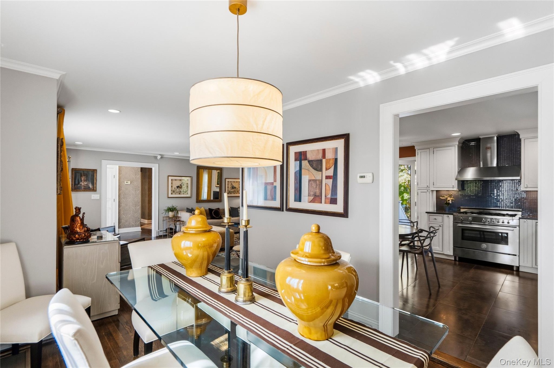 Neutral-toned interior featuring hardwood flooring, a cylindrical pendant light fixture, crown molding, and recessed lighting