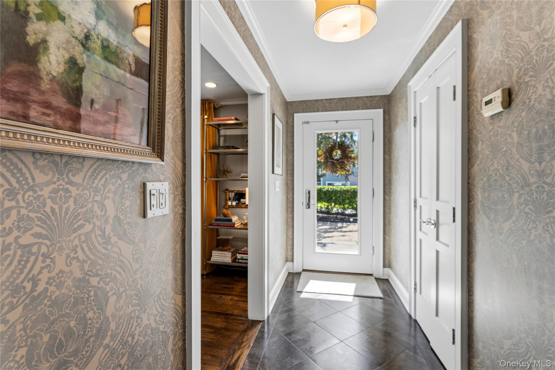 Entryway featuring patterned wallpaper, tile flooring, a glass-panel entry door, and a drum-style ceiling fixture