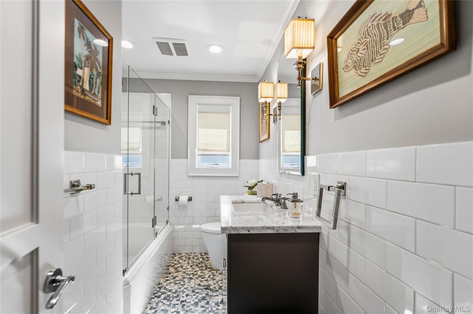 Bathroom featuring white subway tile wall cladding, a Marable countertop vanity with an undermount sink, a shower enclosure with a glass door, and pat