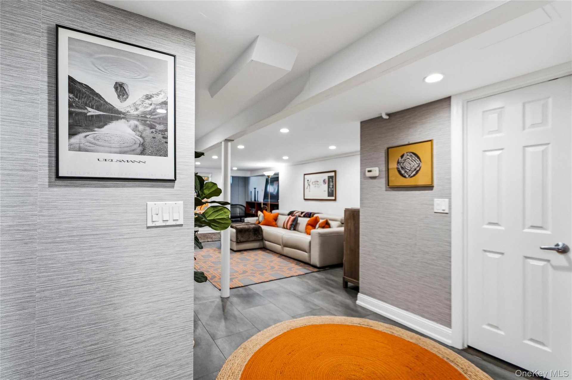 Interior space featuring textured grey wall coverings, recessed ceiling lighting, and large-format tile flooring