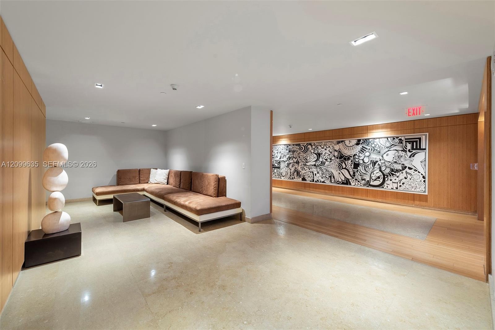 Warm wood paneling, polished concrete flooring, recessed lighting, and a modern lounge seating area