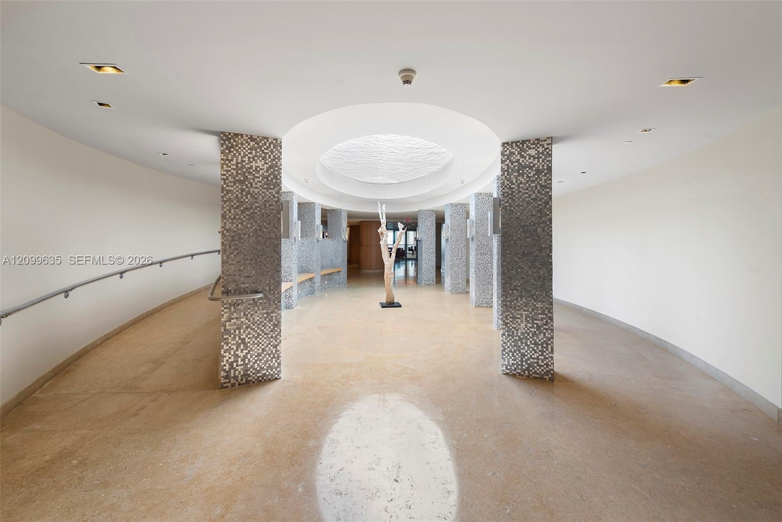 Sophisticated commercial or gallery space featuring soaring ceilings with recessed lighting, polished concrete flooring, and distinctive textured ston