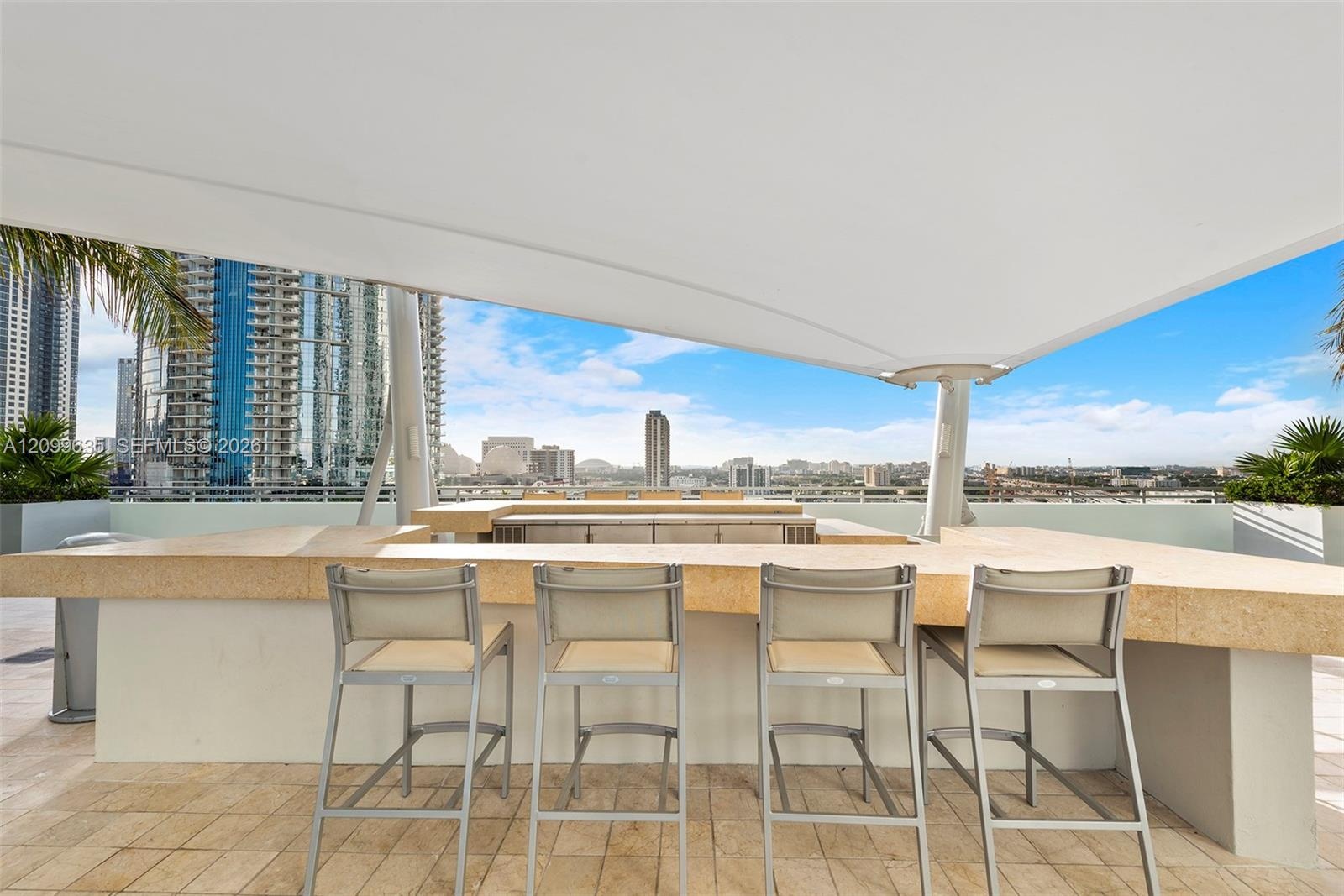Rooftop lounge area featuring a shade canopy, built-in bar, and city skyline