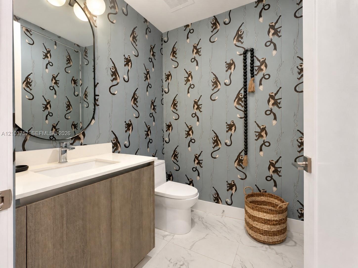 Wood-finish vanity with an integrated rectangular sink, wall-mounted oval mirror, and a three-light vanity fixture