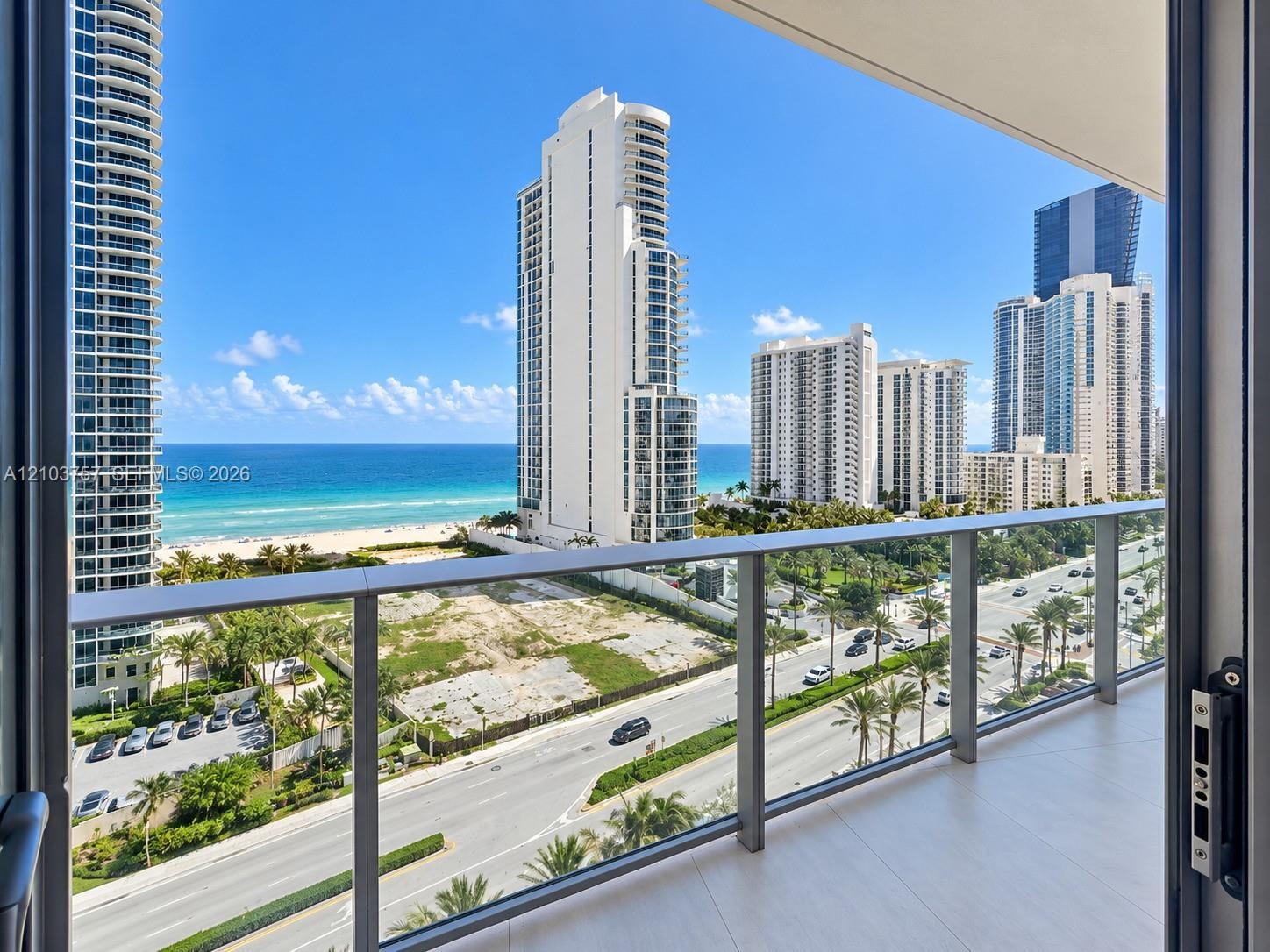 Balcony with glass panel railings, wood-finish flooring, and coastal scenery