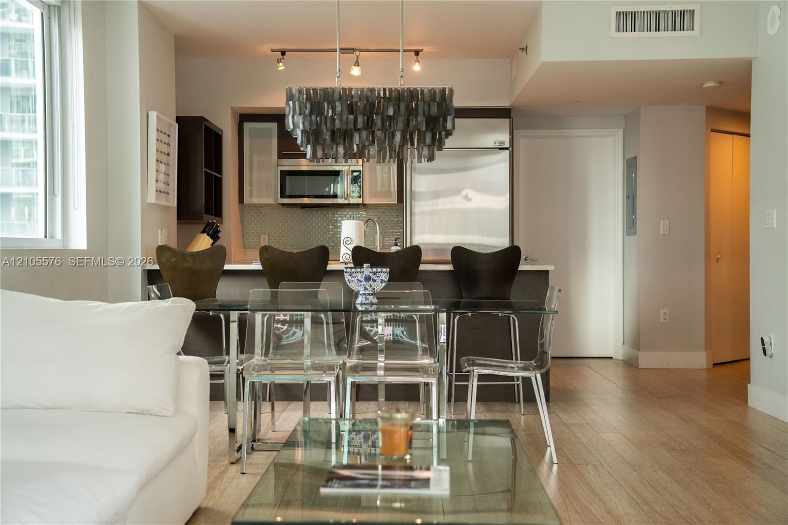 Open-concept kitchen featuring dark-finish cabinetry, stainless steel appliances, and wood-finish flooring, complemented by a distinctive multi-tiered