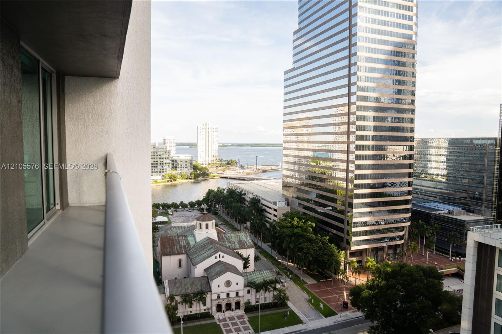 Private balcony with a metal railing, overlooking urban architecture and a water corridor