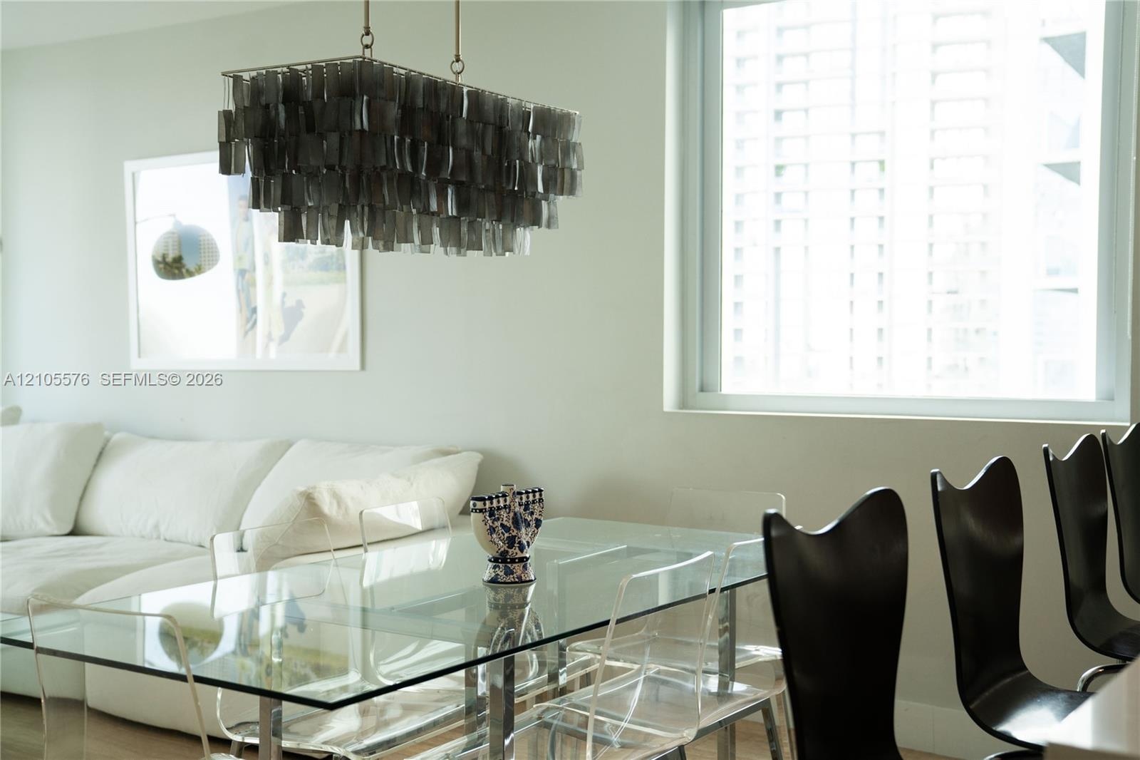 Rectangular tiered chandelier with dark metallic finish and large, expansive window with aluminum framing