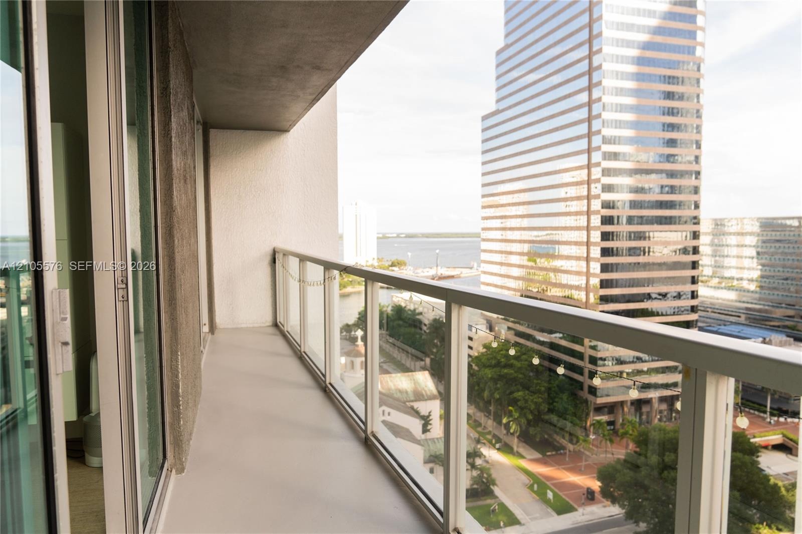 Covered balcony featuring a glass and metal railing, concrete flooring, and sliding glass entry doors