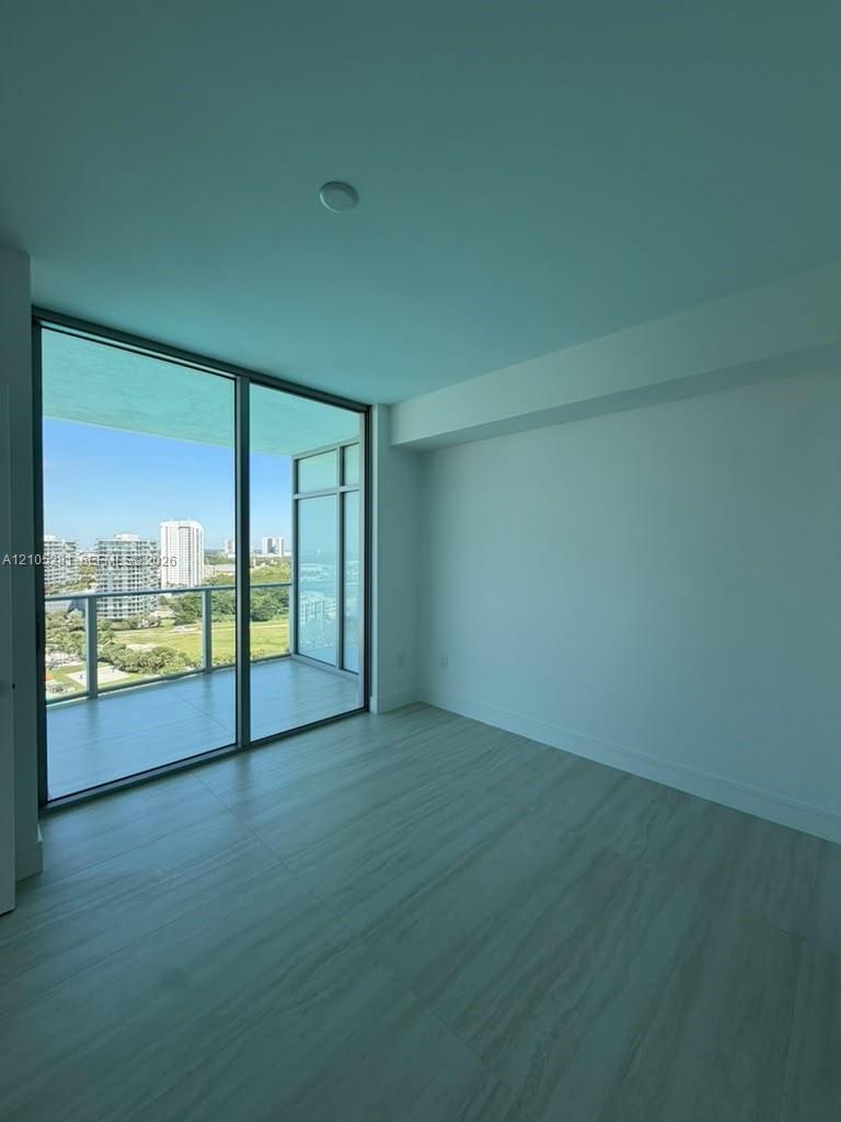 Floor-to-ceiling glass windows, expansive private balcony with glass railing, and large-format tile flooring