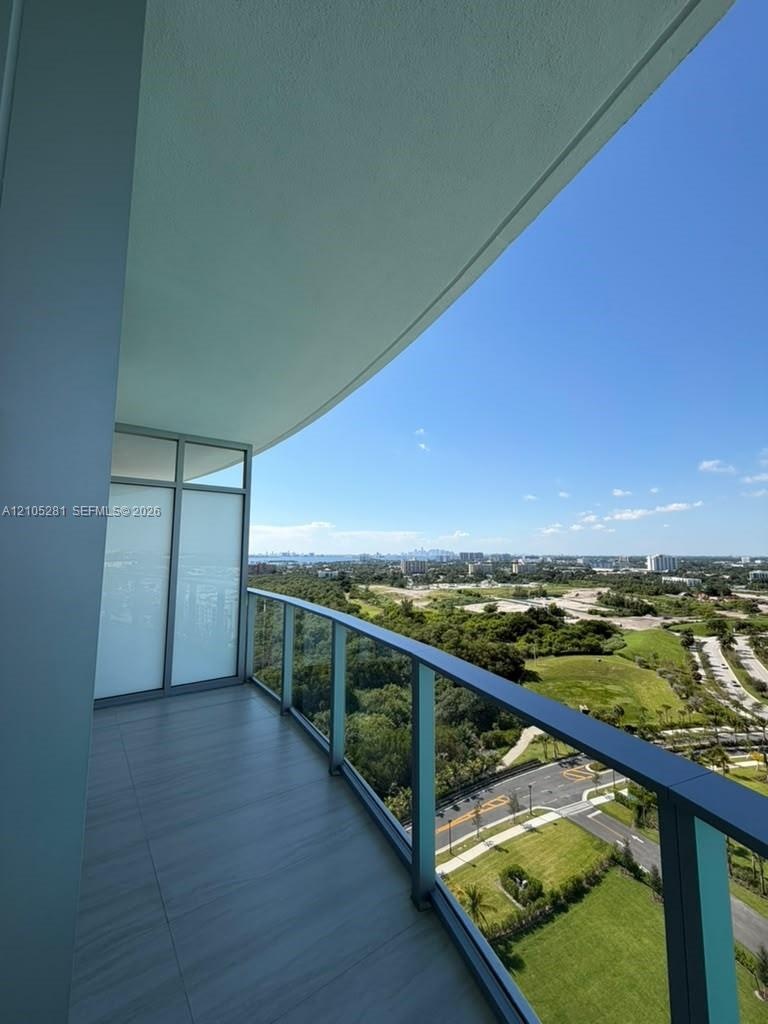 Private balcony featuring tile flooring, a glass panel railing, and an expansive skyline horizon