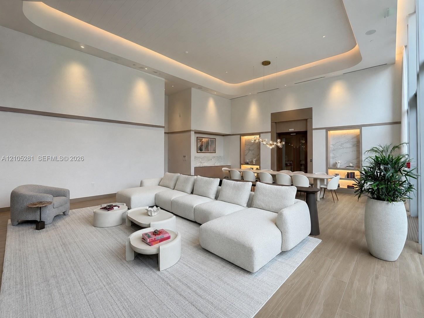 High ceilings with integrated cove lighting, recessed ceiling accents, built-in recessed wall shelving with stone-finish backings, and wood-finish flo