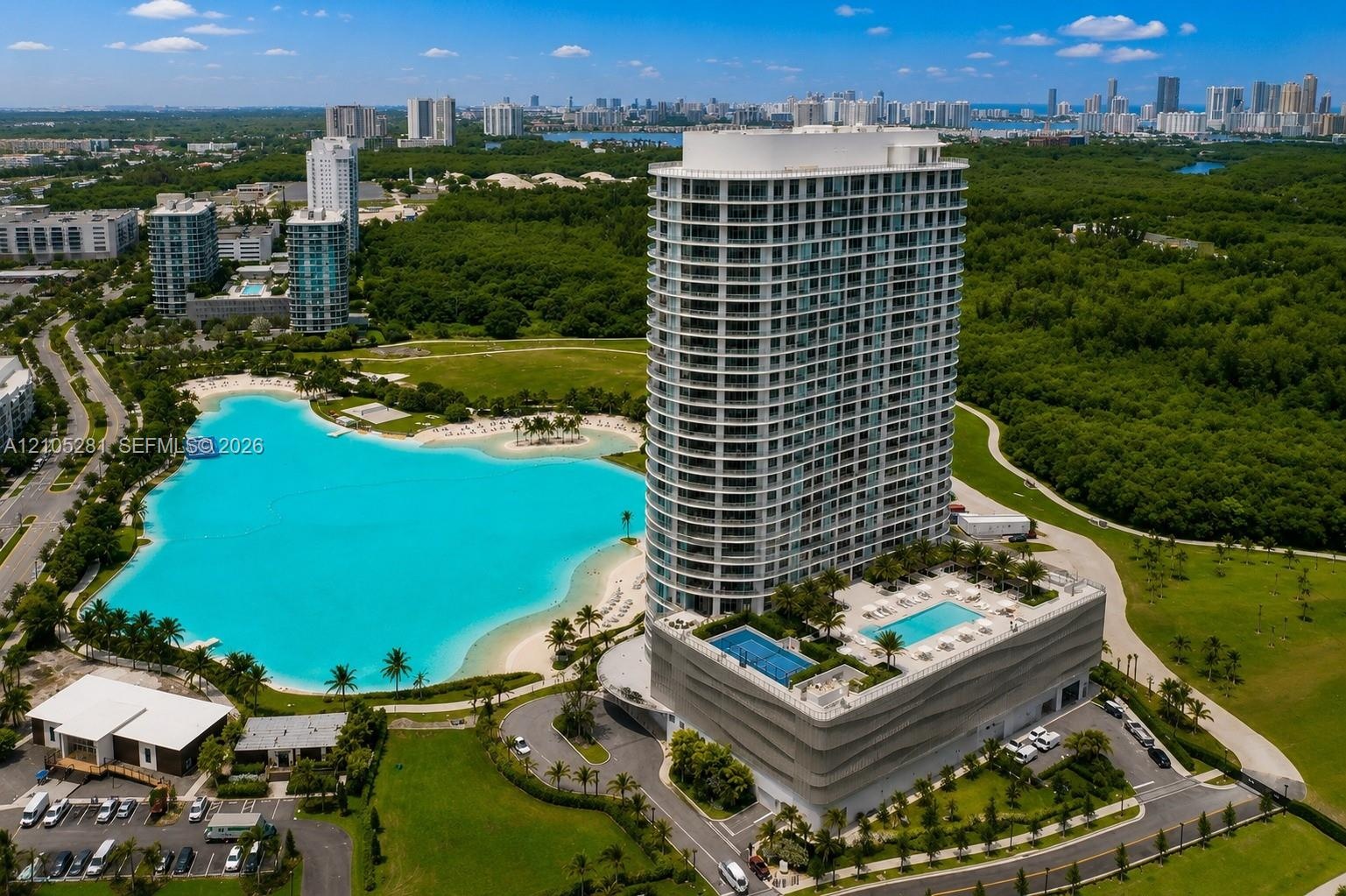 High-rise residential tower featuring a tiered podium with multiple swimming pools, expansive man-made lagoon, and tropical landscaping