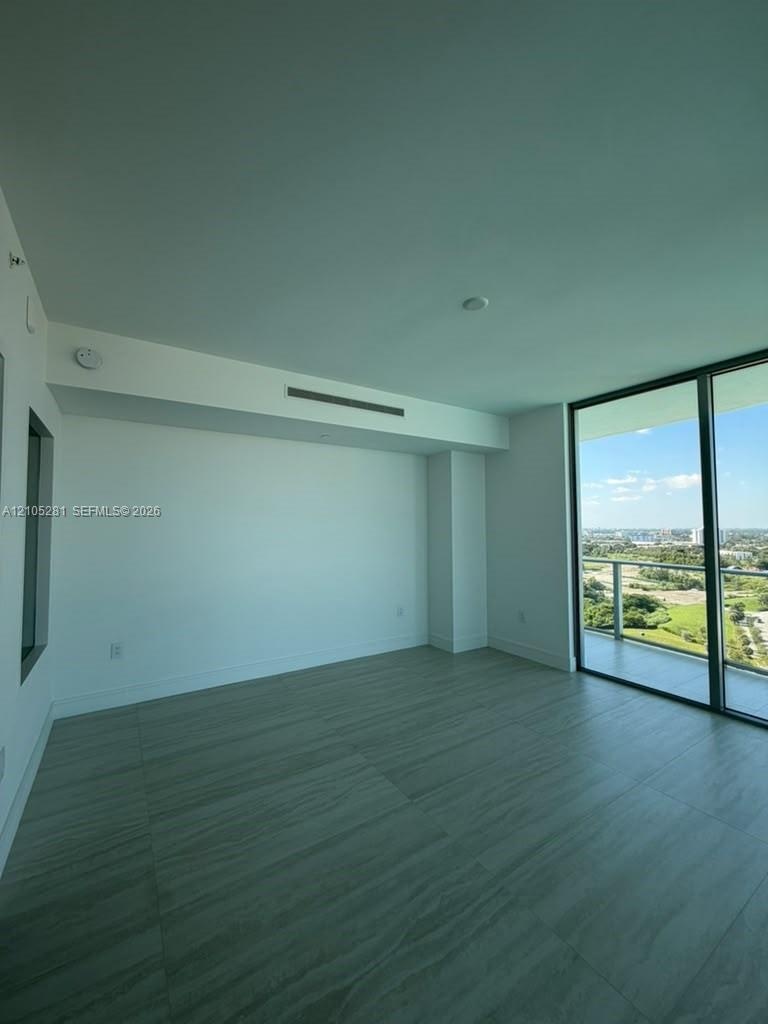 Floor-to-ceiling glass sliding doors, private balcony, wood-finish tile flooring, recessed ceiling HVAC, and neutral wall finishes