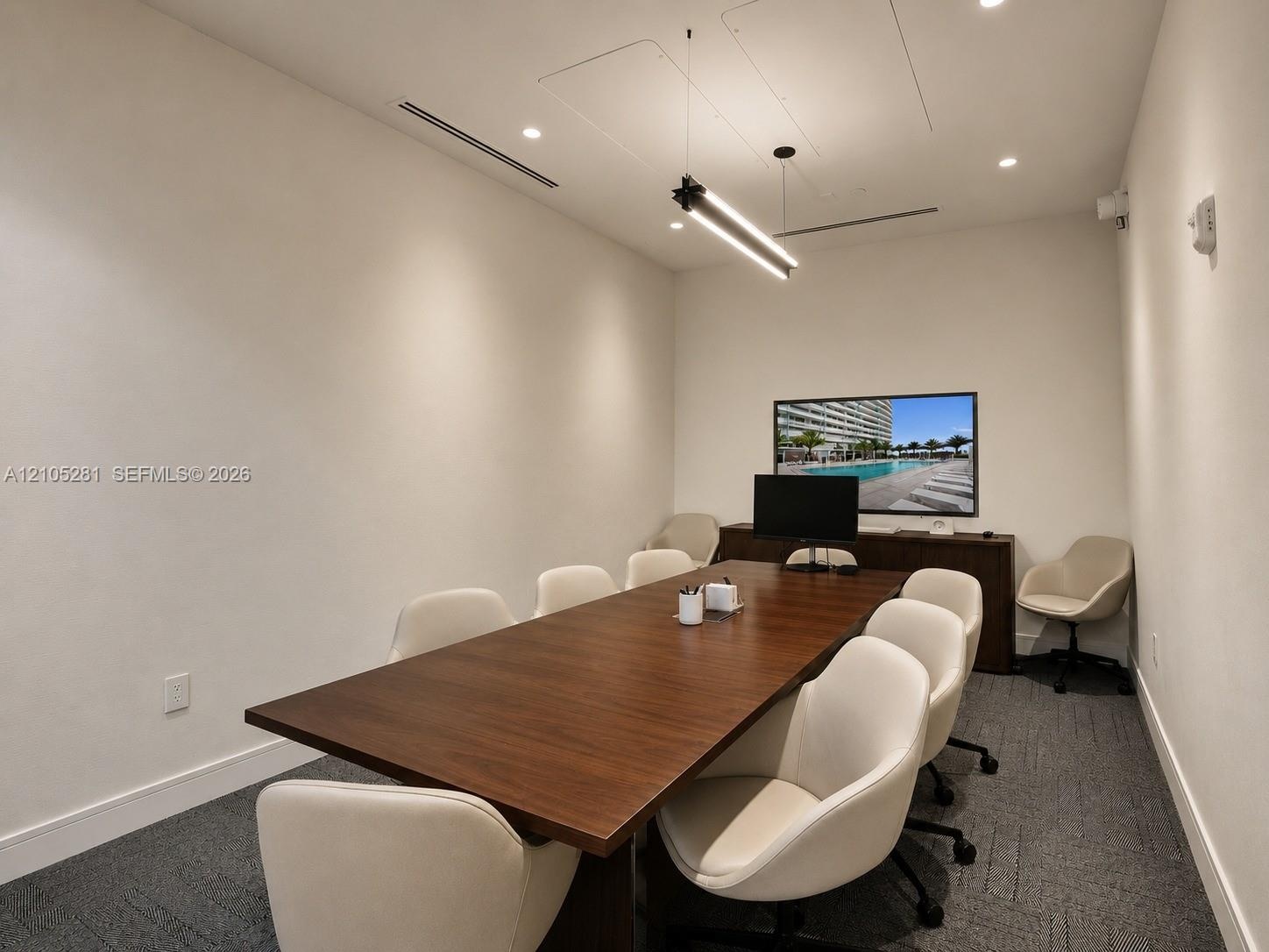 Interior room featuring linear LED pendant lighting, recessed ceiling lights, dark-toned carpet flooring, and a built-in dark wood console