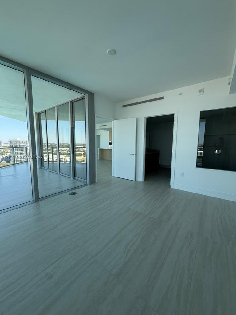 Floor-to-ceiling glass panel walls, light-toned wood-finish flooring, and recessed ceiling lighting