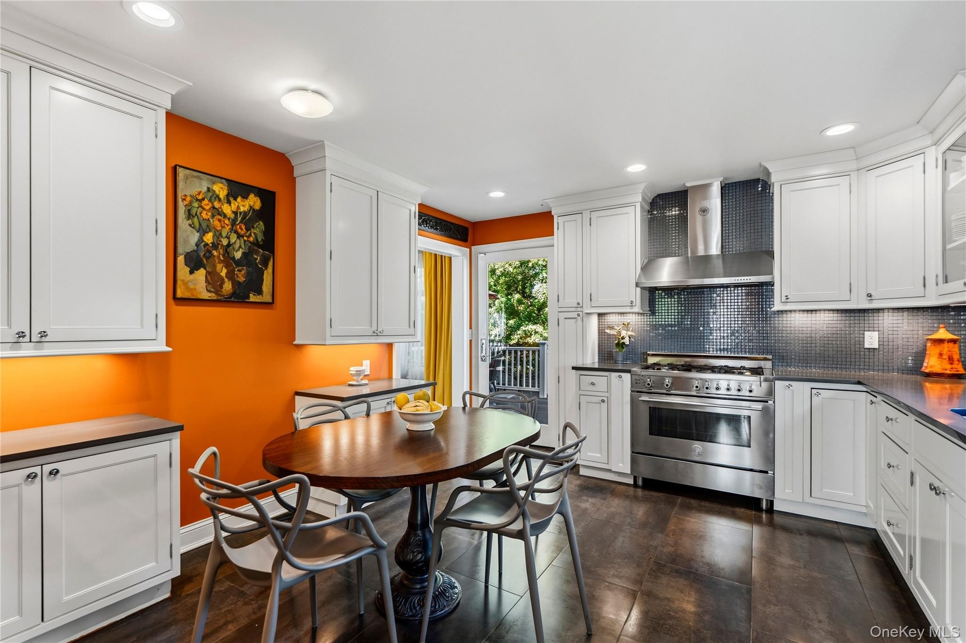 Kitchen featuring white cabinetry, stainless steel gas range with professional-style hood, dark mosaic tile backsplash, and dark tile flooring