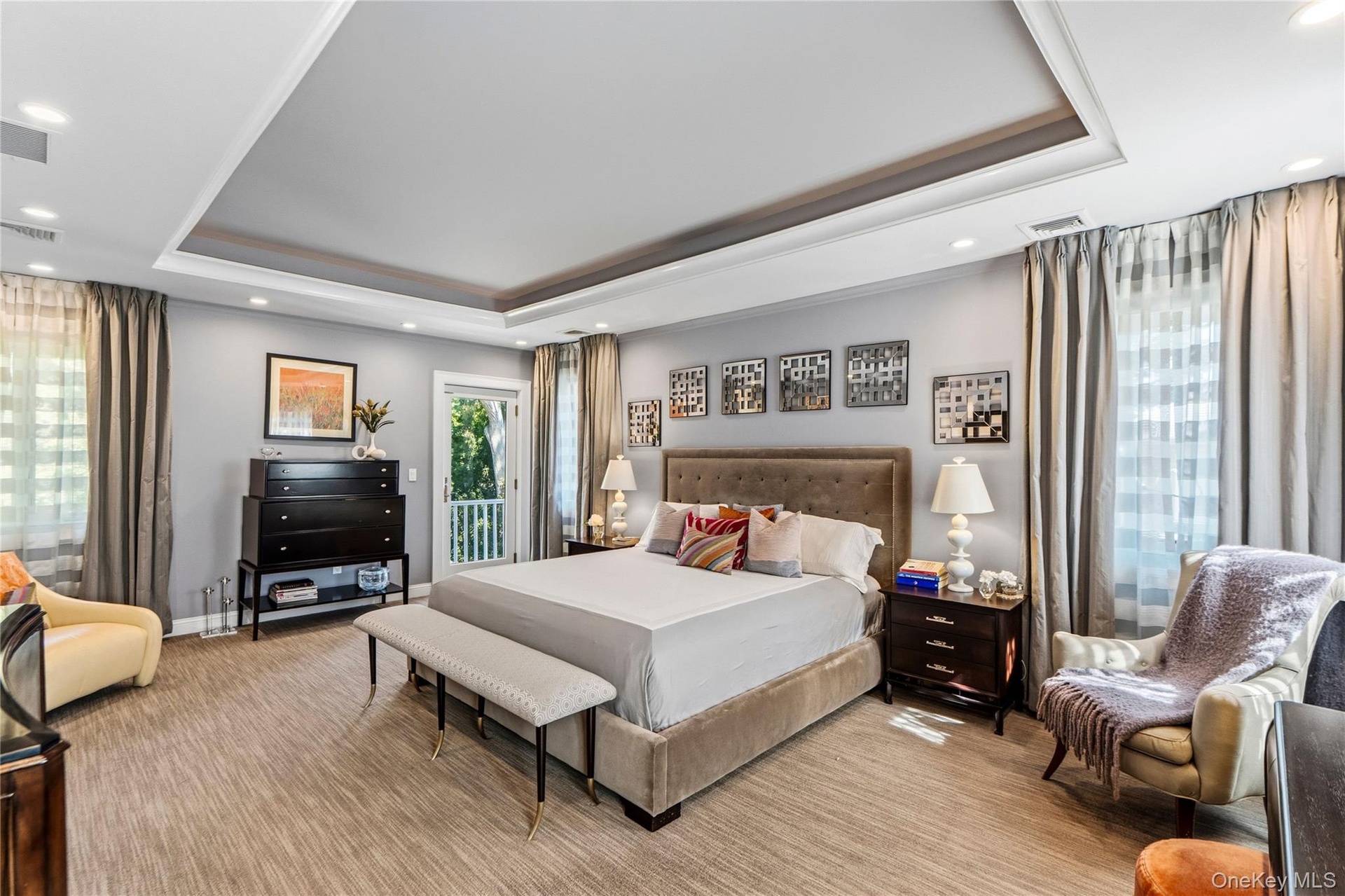 Tray ceiling with recessed lighting, integrated wall-to-wall carpeting, multiple windows with neutral drapery, and a glass-paneled exterior door