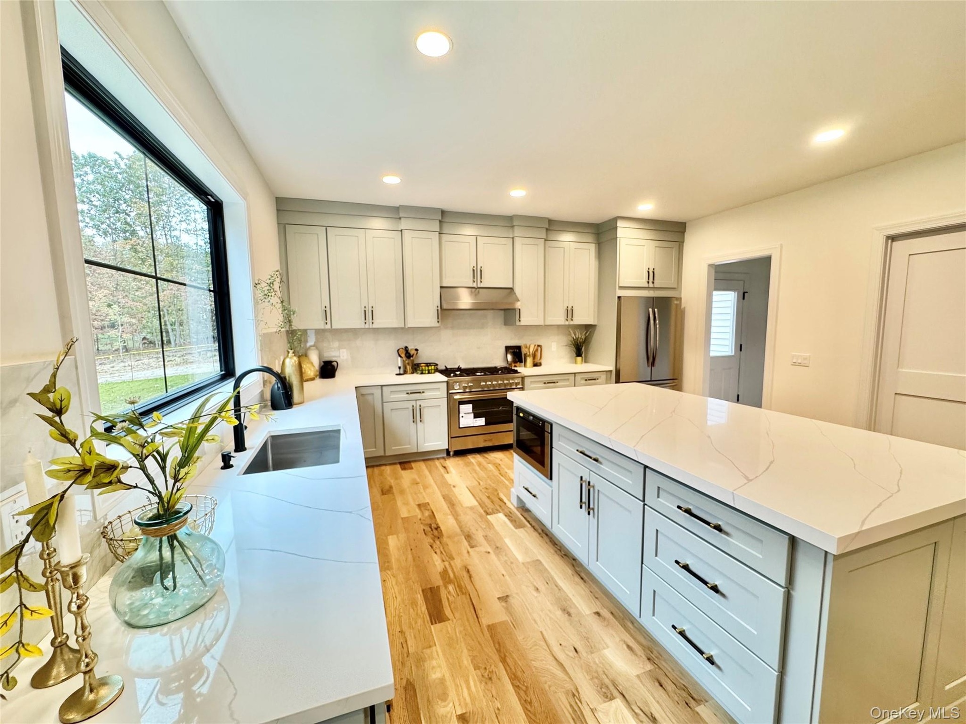 Kitchen with light stone counters, stainless steel appliances, tasteful backsplash, a center island, and recessed lighting