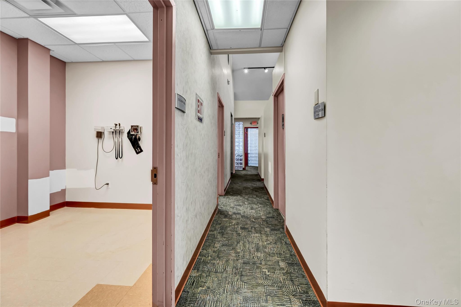 Hallway featuring dark colored carpet and a paneled ceiling
