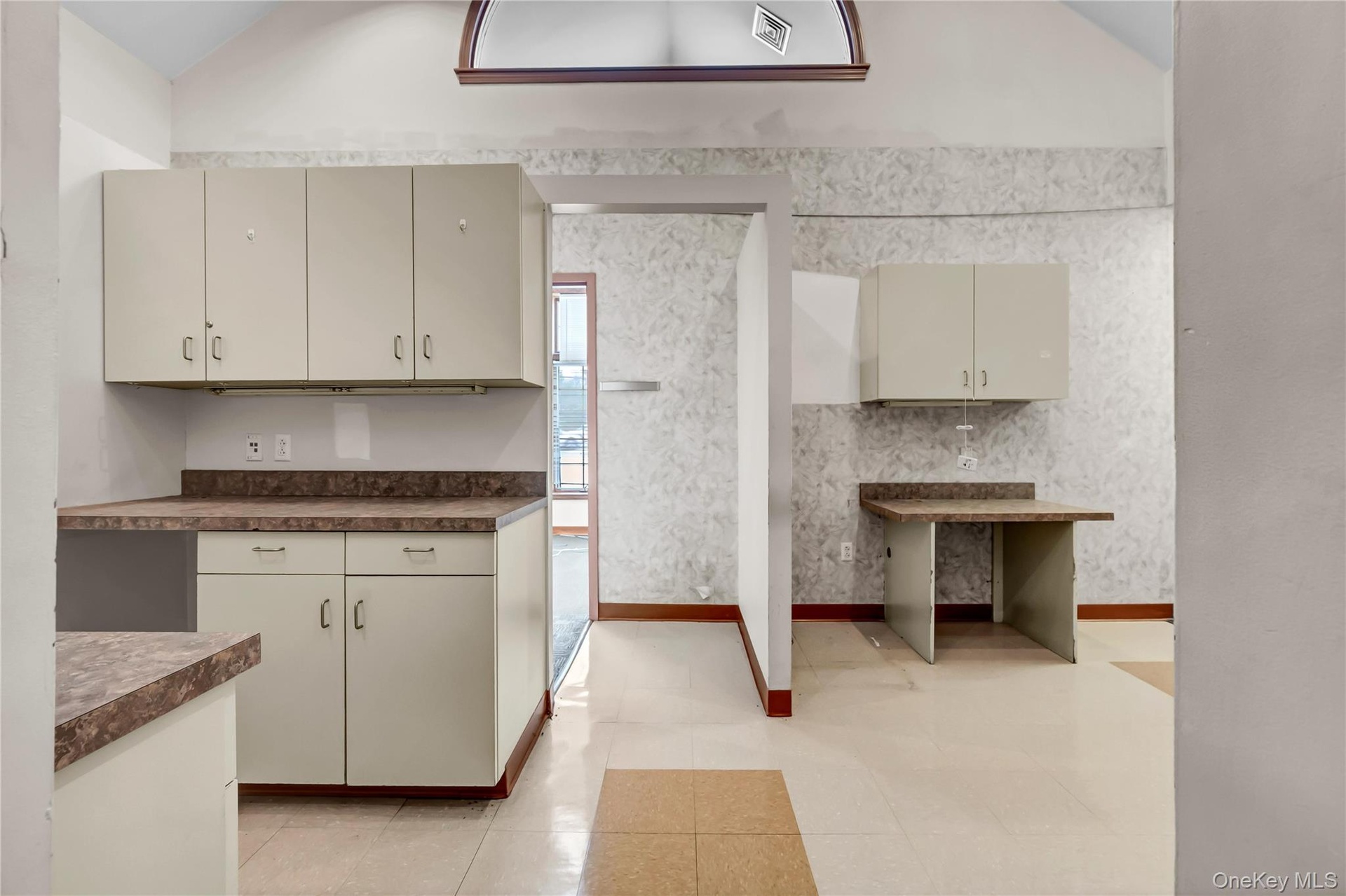 Kitchen featuring vaulted ceiling, dark countertops, and light tile patterned flooring
