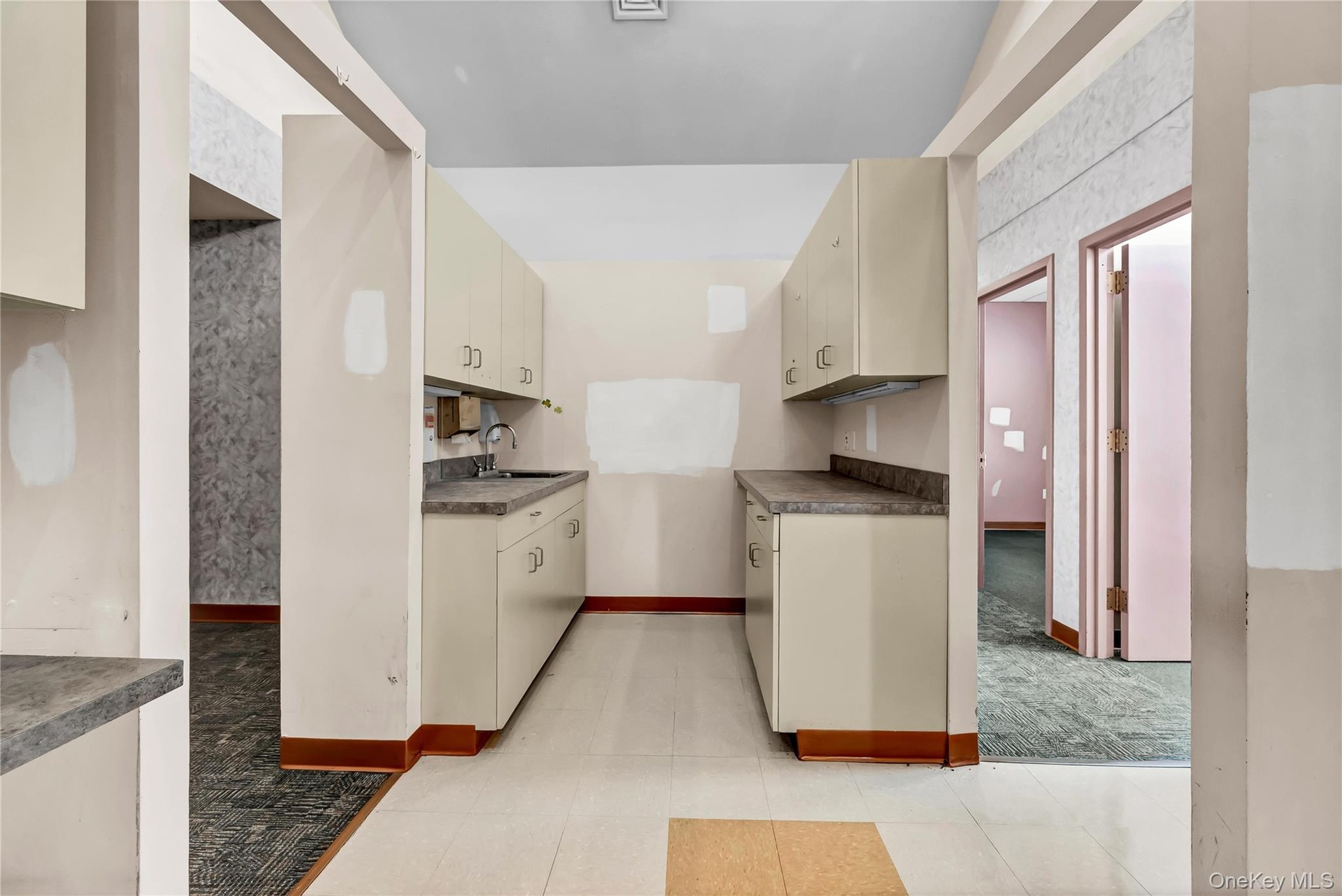 Kitchen featuring cream cabinets, dark countertops, and light carpet