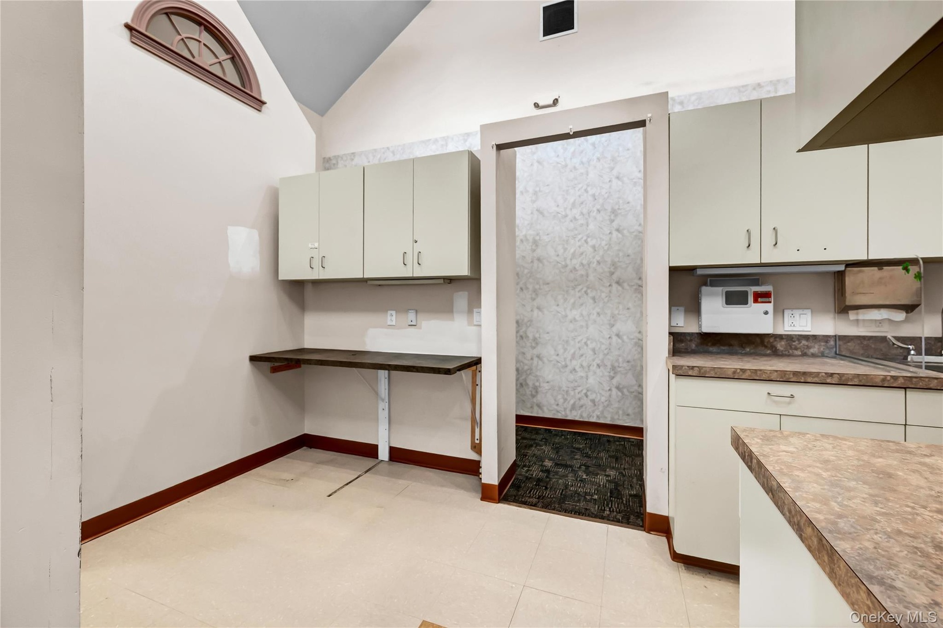 Kitchen featuring vaulted ceiling and baseboards