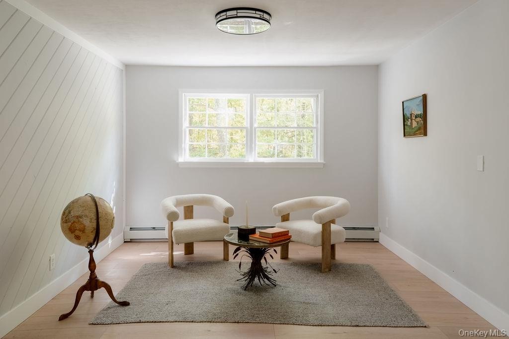 Interior room featuring wood-finish flooring, diagonal-patterned millwork, a double-hung window, and a central flush-mount ceiling fixture