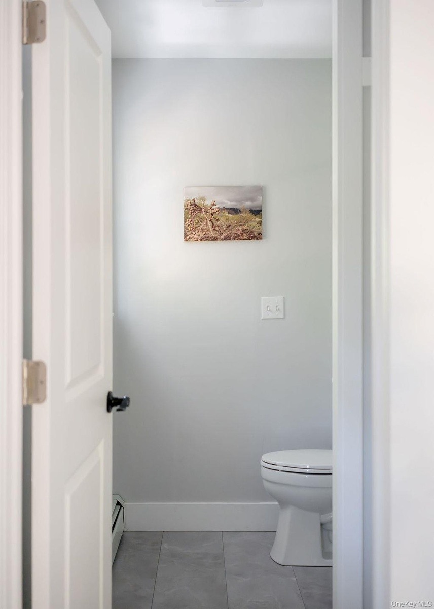 Neutral-toned walls, gray tile flooring, and a white porcelain toilet