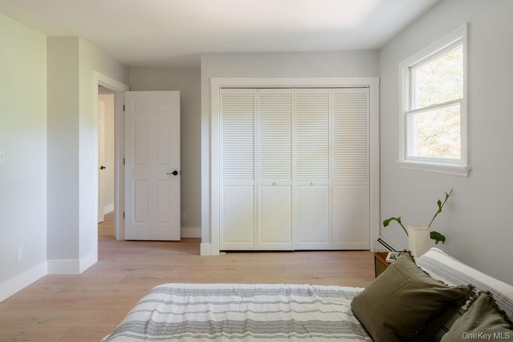Neutral wall palette, wood-finish flooring, four-panel closet with louvered inserts, and a single-hung window
