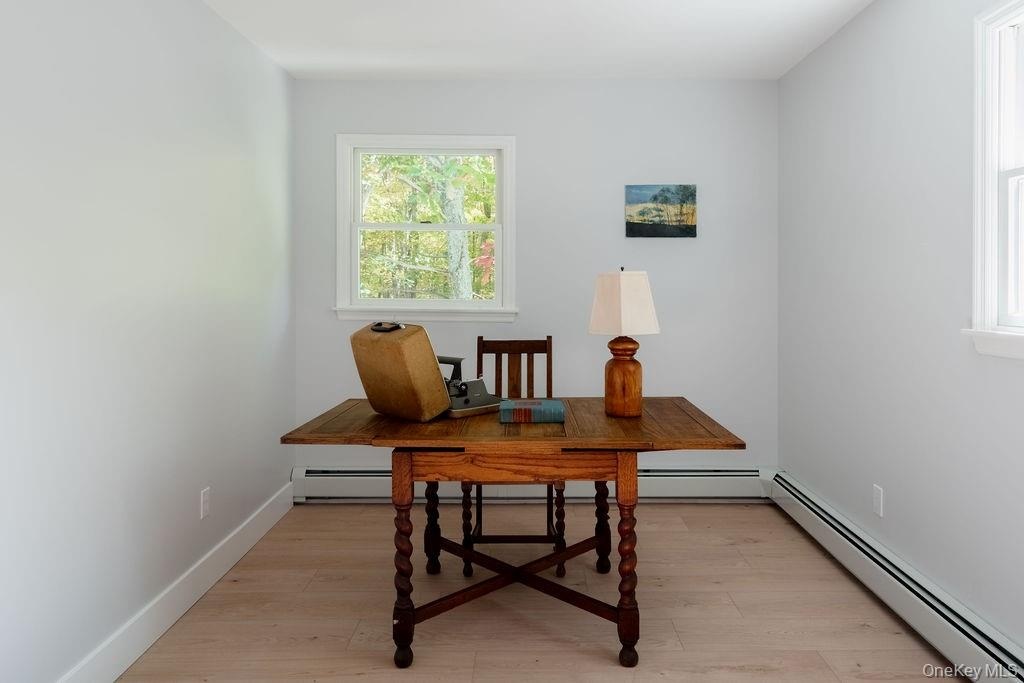 Neutral-toned interior space featuring light wood-finish flooring, two double-hung windows, and crisp white wall trim