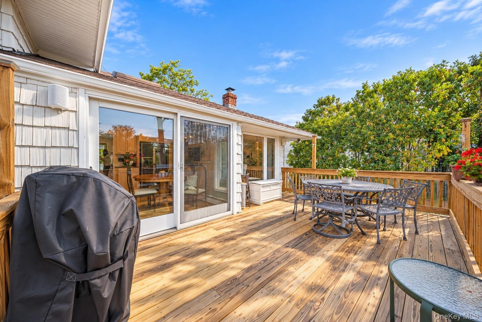 Expansive wood deck with a perimeter railing, light-toned shingle siding, and floor-to-ceiling sliding glass doors