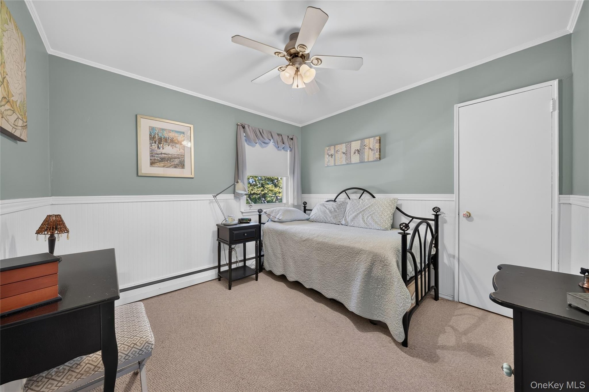 Room featuring beadboard wainscoting, neutral wall paint, carpeting, and a ceiling fan with integrated lighting
