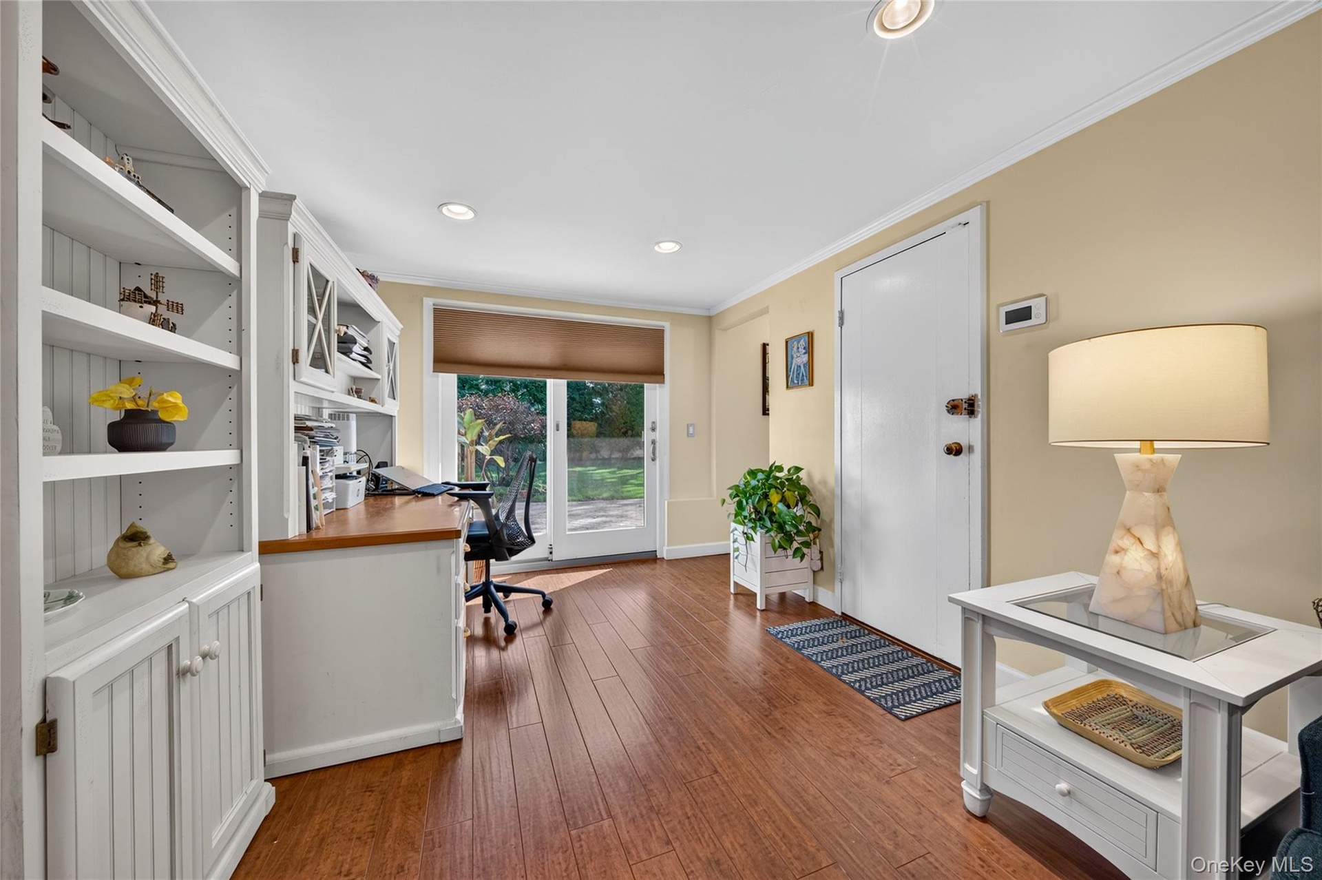 Built-in white cabinetry with open shelving, wood-finish flooring, glass-paned sliding exterior door, and recessed lighting