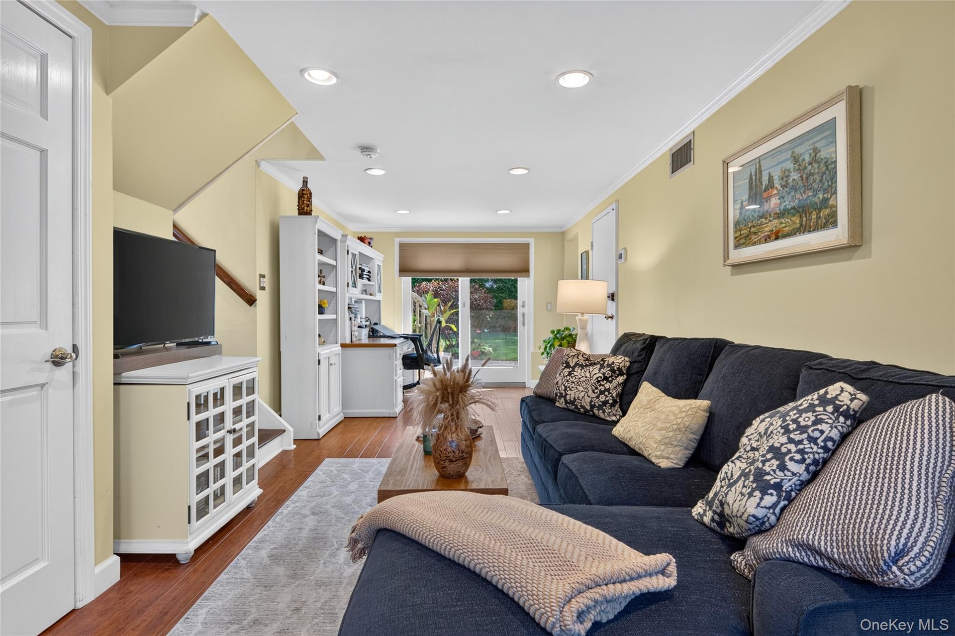 Interior space featuring wood-finish flooring, recessed lighting, crown molding, and built-in cabinetry with integrated shelving