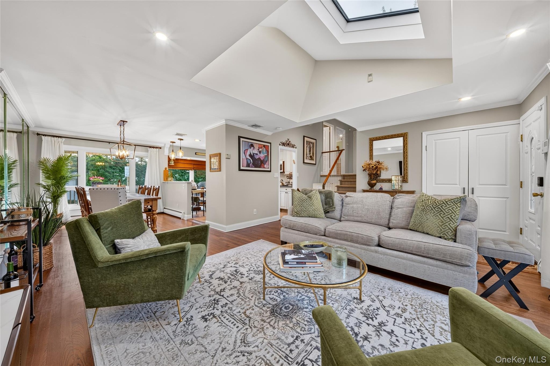 Vaulted ceiling featuring a large central skylight, recessed lighting, and wood-finish flooring