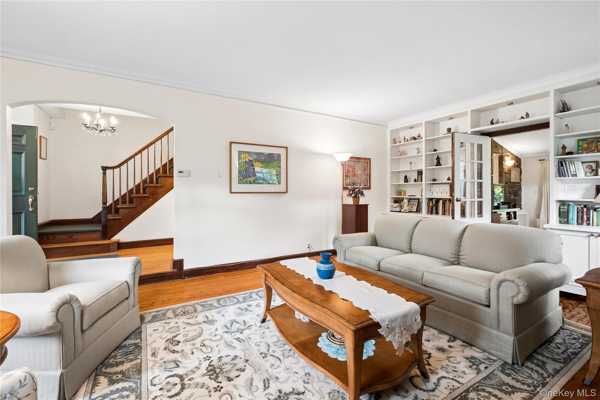 Living Room with built-in shelves and storage cabinets and view of entrance foyer