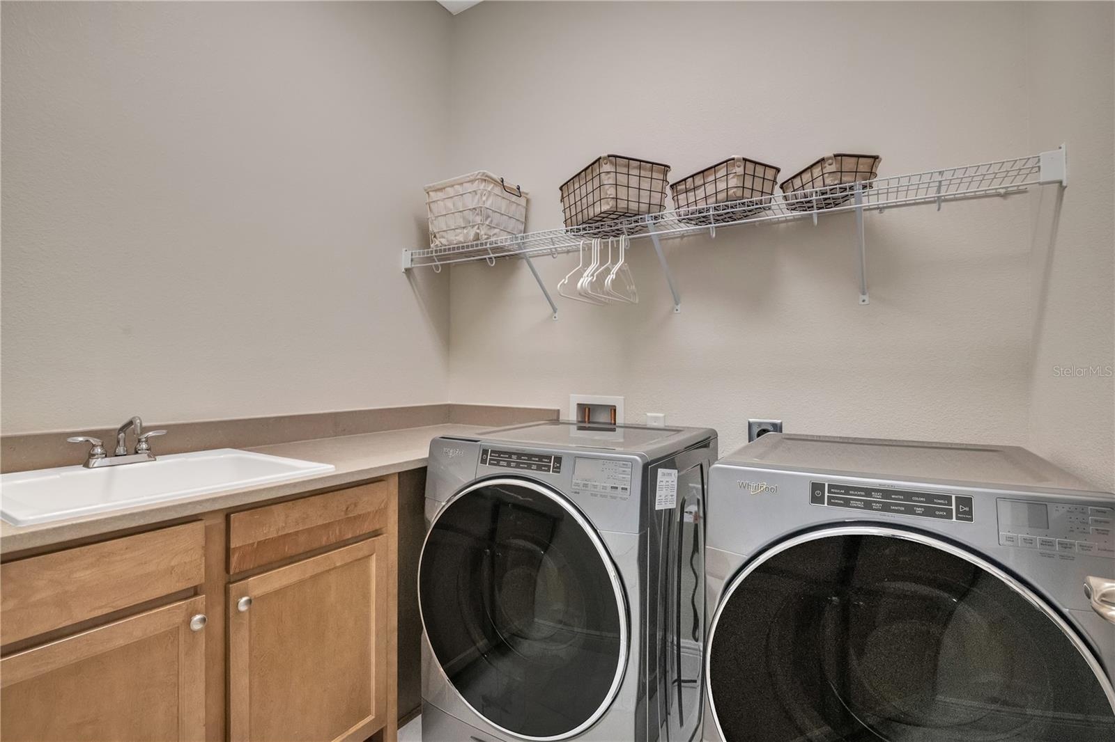 Spacious laundry room with utility sink, cabinetry, and convenient storage.