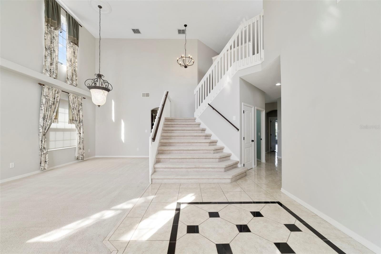 Inside, ETCHED-GLASS FRENCH DOORS open to a welcoming foyer with a SOARING CEILING and decorative tile flooring, setting the stage for the generous li