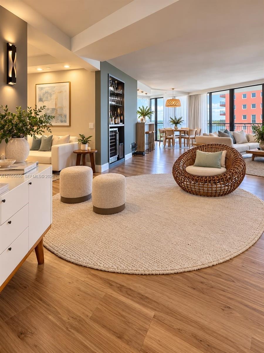 Wood-finish flooring throughout featuring a built-in recessed wet bar with integrated beverage refrigeration, expansive floor-to-ceiling windows, and 