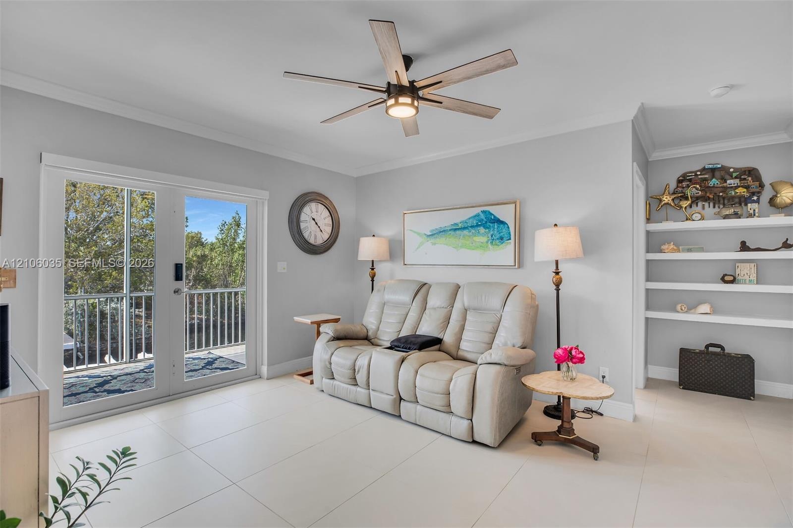 Large-format tile flooring, double glass door with integrated railing, contemporary ceiling fan with light fixture, and built-in wall shelving