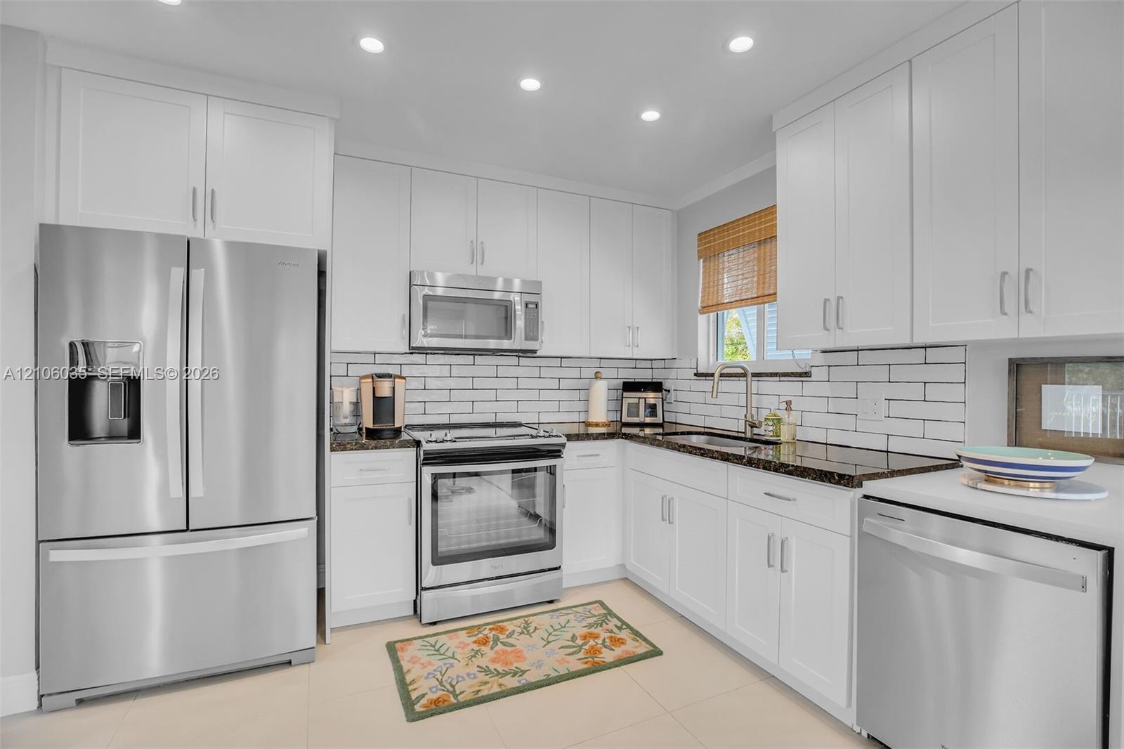 Kitchen featuring white shaker cabinetry, dark stone countertops, stainless steel appliances, subway tile backsplash, and recessed ceiling lighting