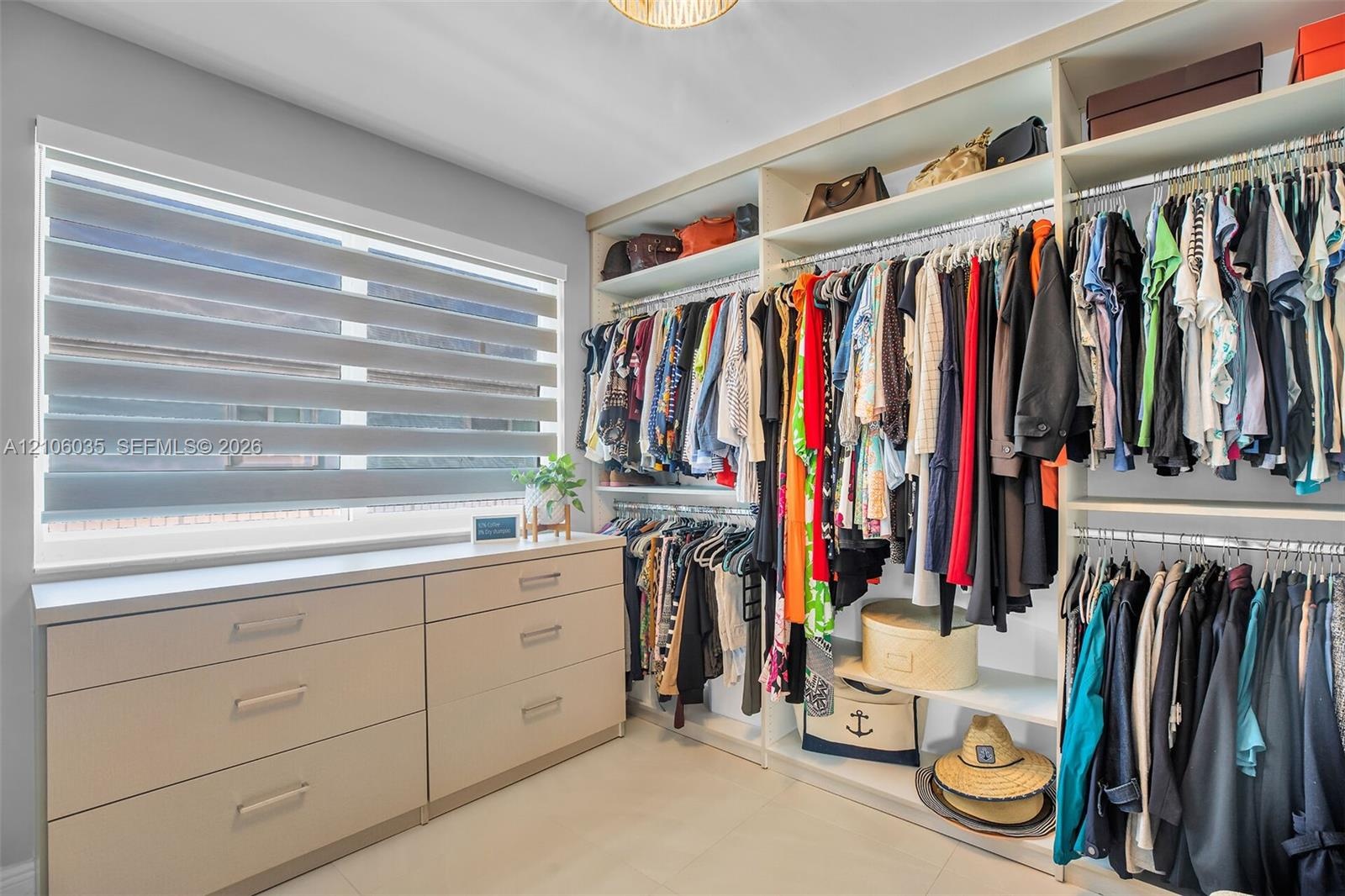 Custom walk-in closet featuring extensive built-in shelving, hanging rods, integrated drawer storage, and a light-filtering window shade