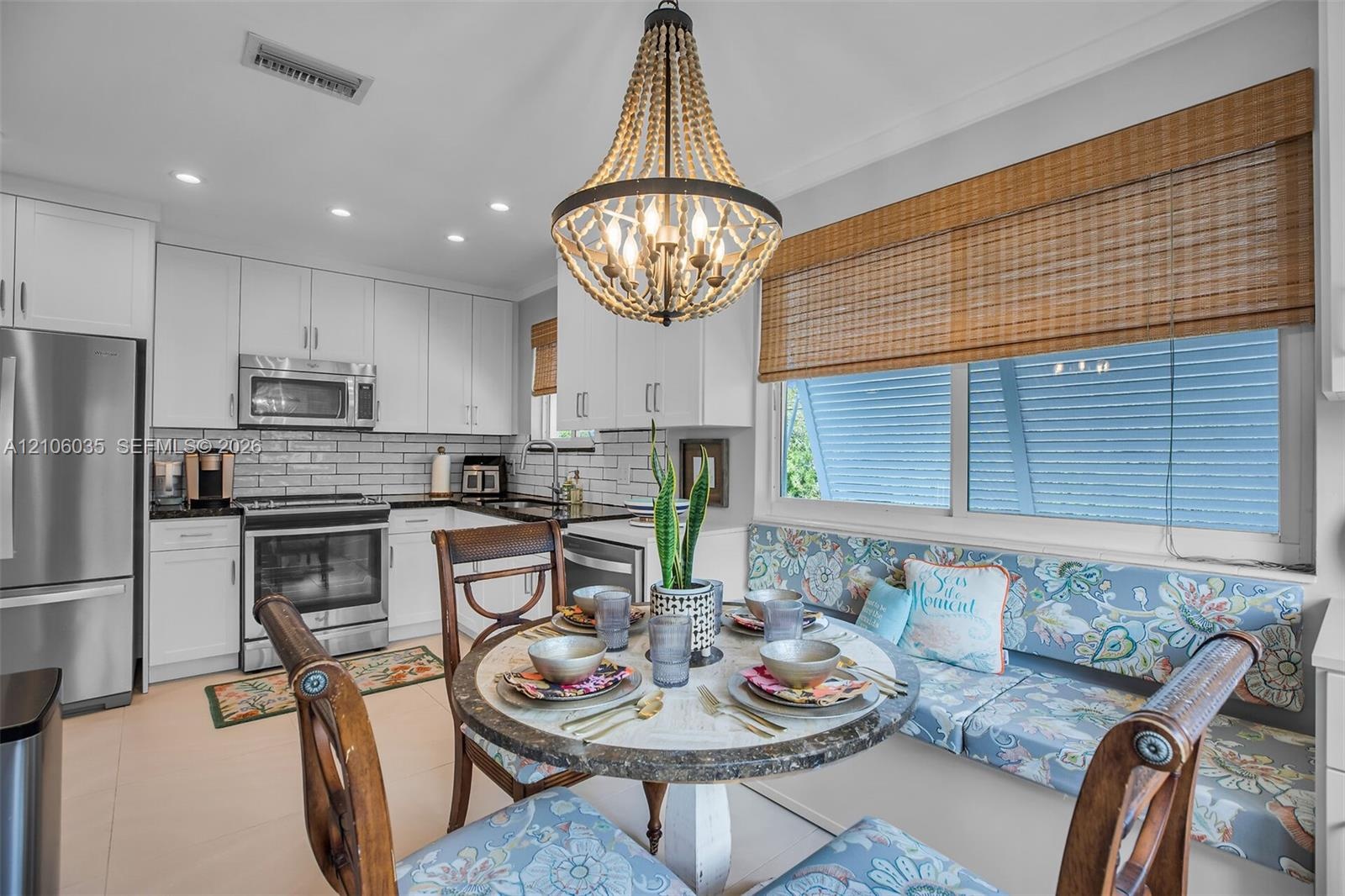 Kitchen featuring white shaker-style cabinetry, stainless steel appliances, subway tile backsplash, recessed lighting, and a built-in banquette seatin