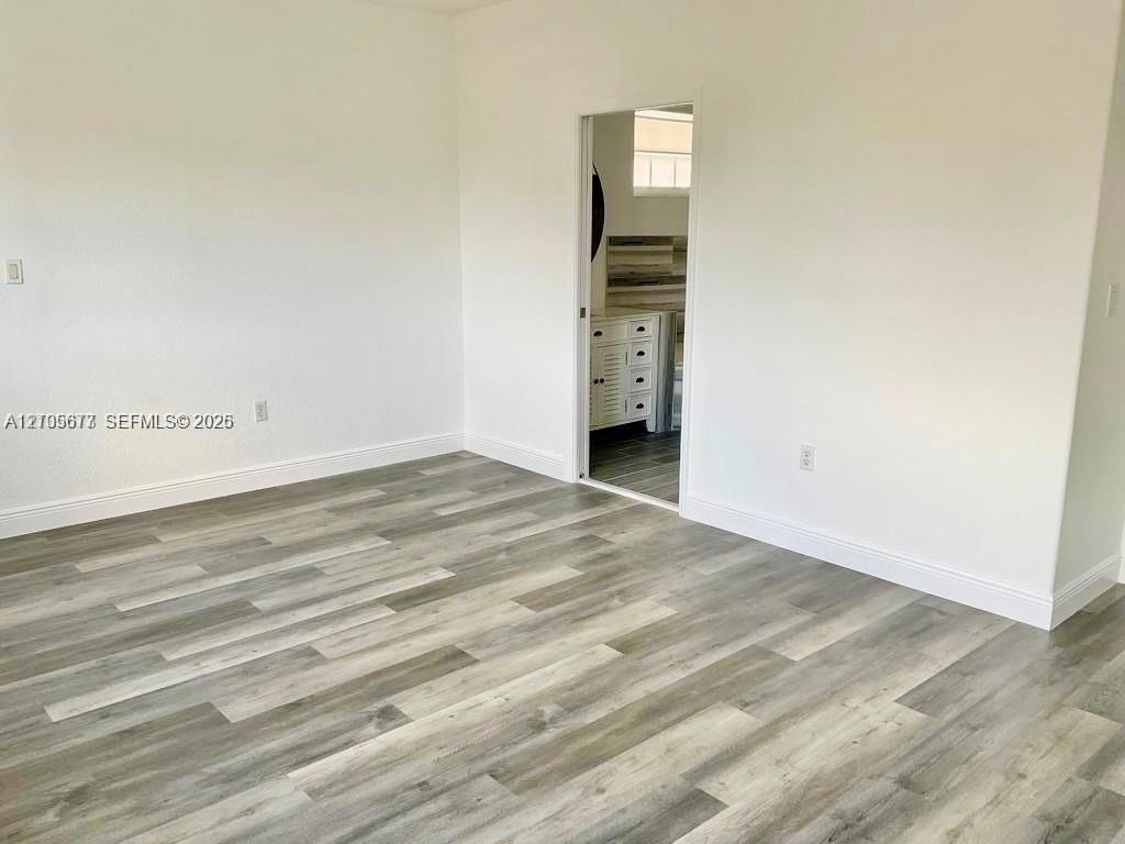 Interior space featuring wood-finish flooring, smooth-finish walls, and a white vanity cabinet with drawers